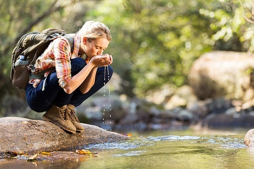 Woman Drinking Water on Creek